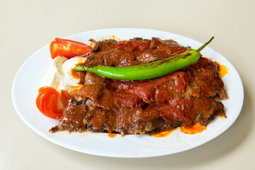Turkish and Arabic Traditional Ramadan doner kebab with tasty tomato sauce and rice or turkish pilav in white plate on wood table background. ( , Iskender, ekmek arasi pilav ustu doner, doner durum )