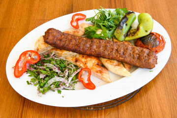 Grilled Turkish Adana, Urfa  Kebab with grilled vegetables, onion and rice on plate. Adana durum.
