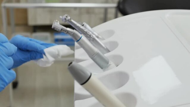 the hands of a nurse in blue gloves wipe the working dental equipment with a cleaning solution using a napkin, Disinfection of medical equipment, Slow motion