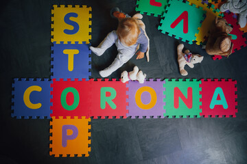 bird view of colorful kids puzzle mat with letters like STOP CORONA and Covid written on them lying...