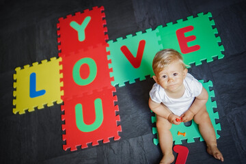 bird view of colorful kids puzzle mat playground in nursery with letters like Baby Love written on...