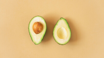 Organic avocado with seed, avocado halves and whole fruits on orange background. Top view, creative summer food concept.