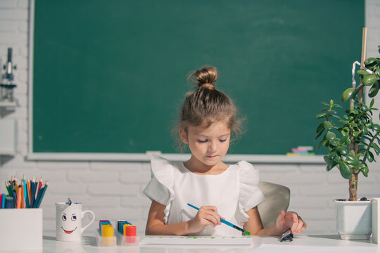 Cute little preschooler child girl drawing at school. Child girl painting on elementary school. Childhood learning, kids artistics skills.