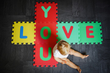 bird view of colorful kids puzzle mat playground in nursery with letters like Baby Love written on...
