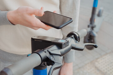 A man scans an electric scooter qr-code for rent