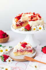 Strawberry vanilla cake on a white cake stand, with wooden forks and strawberries 