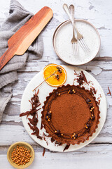 Chocolate caramel tart with dry orange sliceon a white ceramic with fork on a wooden surface
