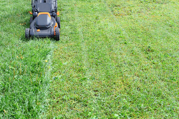 An image of a black and orange lawn mower used for lawn maintenance.   