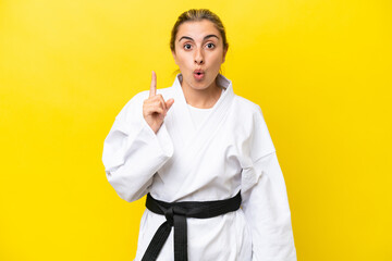 Young caucasian woman doing karate isolated on yellow background intending to realizes the solution while lifting a finger up