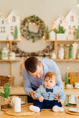 dad and baby son in the decorated for the new year kitchen. father's day