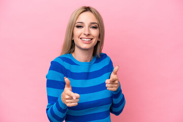 Pretty blonde woman isolated on pink background pointing to the front and smiling