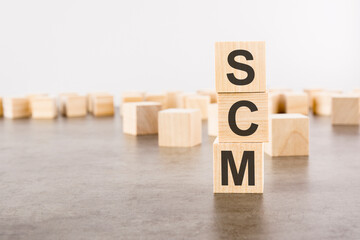 SCM text as a symbol on cube wooden blocks. many wooden blocks in the background.