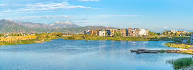 Residential buildings near the Oquirrh Lake with docks and view of mountains at the back