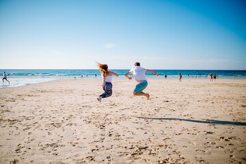 Two people jumping on the beach
