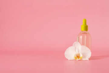 Fototapeta na wymiar Hyaluronic acid in a glass bottle with pipettewith orchid flower isolated on pink background with clipping path, Liquid gel or serum, skin care cosmetics.