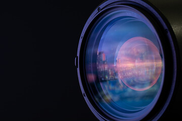Marco shot of a lens in front of black background with reflection of European city