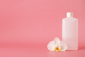 Obraz na płótnie Canvas white plastic bottle for hand sanitizer with orchid flower isolated on pink background.