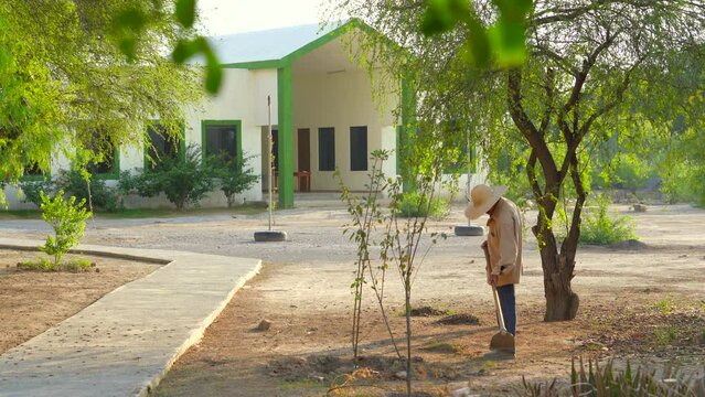 Hombre de sombrero trabajador preparando la tierra y limpiando en el campo