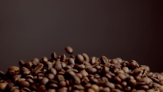 Coffee beans falling down on heap close up. Roasted grains pouring background. 