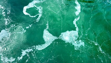 white streaks on the emerald green water of a river or ocean is perfect For text for the beginning of an advertising film, life is seething empty space For text room decoration picture. High quality