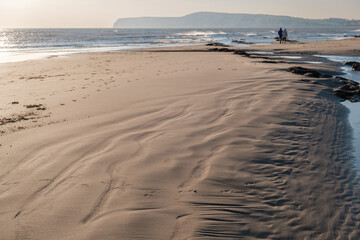 Couple walking in the distance on a sandy beach