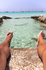 feet on a turquoise paradise beach and stone pool al boats