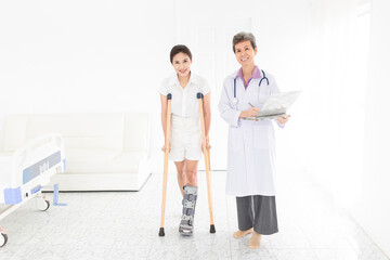 Obraz premium asian patient learning to use crutches with doctor, walk training and rehabilitation, doctor assessment of patient leg, patient wear air cast walking boot