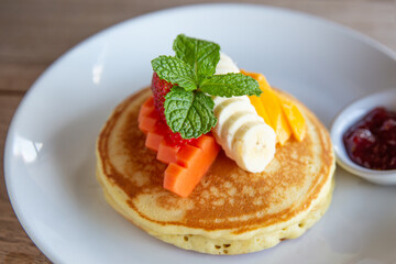 Pancakes with banana, mango, mint and strawberry jam for a breakfast.