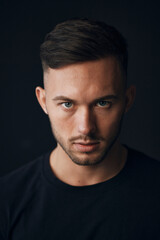 Fototapeta premium Modelling snapshots. Evil self-confident tanned attractive handsome man in classic suit jacket looks at camera posing isolated in black studio background. Fashion offer. Copy space for ad. Closeup