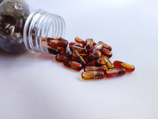 Brown medical pill and tablet spilling out of medicine bottle isolated on white background