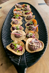 Vegan tapas, served on a black leaf-shaped platter