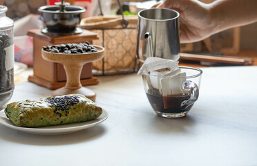 Drip coffee in a bag, drip in a clear coffee mug.