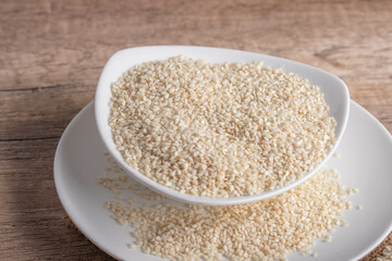 white sesame in white ceramic cup on wooden background