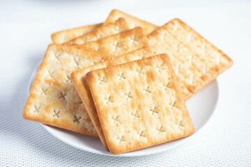 A pile of dry, thin crackers in a cup. Natural light.