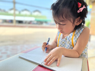 cute little girl writes on her notebook