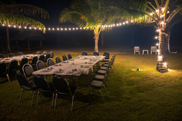group dinner with tables and chairs by beach with light decor
