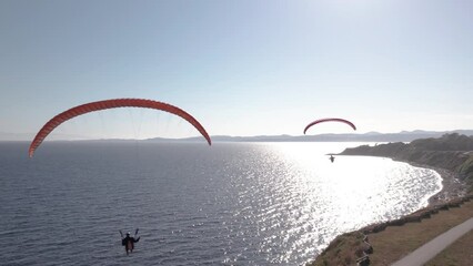 Paragliders beside the ocean, beautiful sunny day, aerial drone footage, soaring, coastline. 4K 24FPS