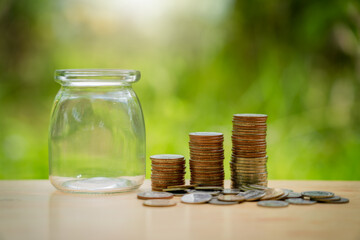 Stacking coins in a jar on wooden , nature background for financial investment and interes . Saving money for wealth, pension retirement and growth of business income concept.