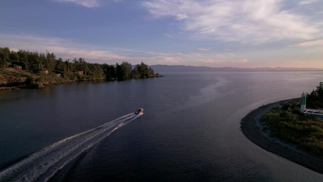 Aerial footage motor boat at sunset, Whiffen Spit, Sooke Harbour, calm water, ocean, Vancouver Island. 5.4K TO 4K 24FPS