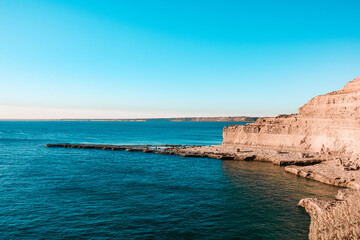 Beautiful landscape of rocky cliff with sea lions during sunset in Valdes Peninsula, a natural reserve of the Patagonian coast of Argentina.