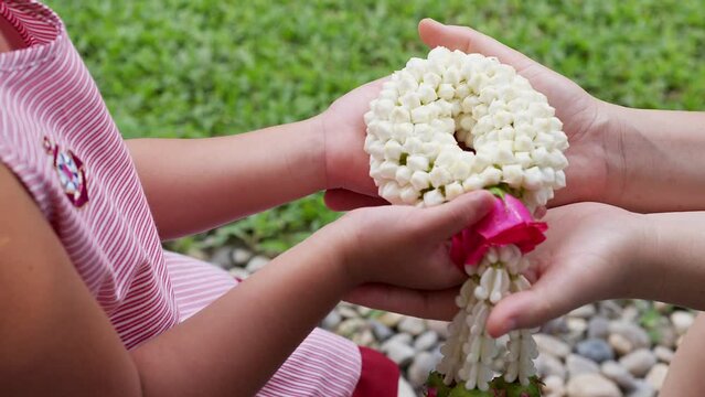 Small girl gives her mother jasmine garland on Thai Mother day.