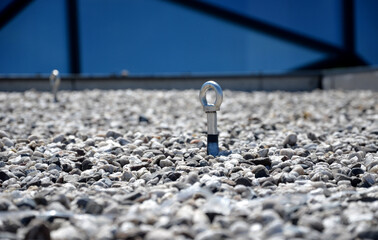 gravel mulch on the roof of a flat green roof. covers and protects layers of insulation and has a decorative effect. handle, staple, eyelet for tying the climbing rope and clips for safe work - Powered by Adobe