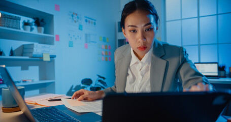 Young Asia cheerful professional woman sitting on desk focus concentrate working on laptop and...