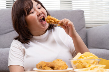 Young Asian oversize women gain weight while eating fried chicken, potato chips and French fried. Junk food that can cause obesity and unhealthy for human body.