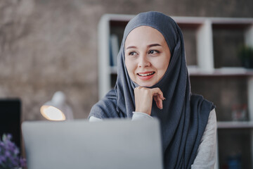 Portrait of a Muslim business woman happily looking at the camera in a hijab at work. smiling arab...