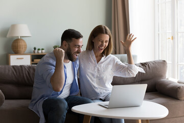 Young couple celebrate online lottery win, screaming with joy looking happy, read great news on laptop, get amazing commercial sale offer or discount. Moment of victory, candid emotions, luck concept