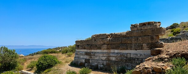 Fototapeta na wymiar Remains of an ancient stone block wall near the sea in Greece.
