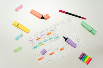 School schedule. A sheet with a handwritten school schedule lies on a white table strewn with colorful markers and stickers. School Time Management