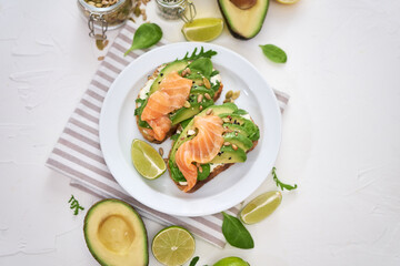 Freshly made Avocado, salmon and cream cheese toasts on a white ceramic plate