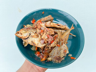 Fried Fish, With a sprinkling of fried onions and chilies served on a plate